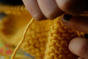 hands knitting yellow yarn